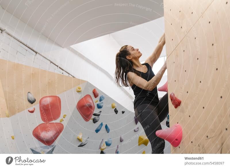 Junge Frau beim Klettern Bouldern an Wand in Kletterhalle Stock
