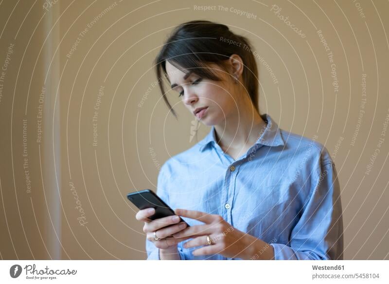 Junge Frau mit Smartphone, Porträt benutzen benützen lesen Lektüre iPhone Smartphones Zuhause zu Hause daheim Nachricht Mitteilung Botschaft junge Frau