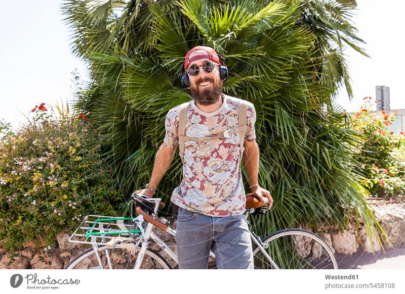 Lächelnder reifer Mann mit Fahrrad T-Shirts Raeder Räder Bike Bikes Fahrräder Rad Rennräder Kopfhoerer Brillen Sonnenbrillen hoeren freuen Glück glücklich sein