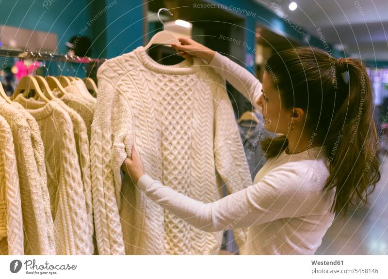 Frau hält einen Pullover in einer Vintage-Boutique altmodisch Kleidung Bekleidung Boutiquen Geschäft Shop Laden Läden Geschäfte Shops weiblich Frauen Shopping