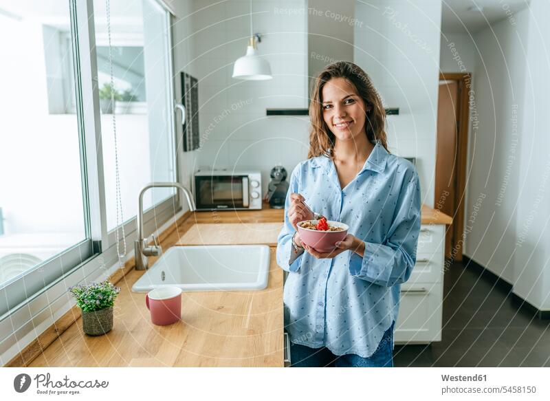 Porträt einer jungen Frau im Pyjama, die in der Küche zu Hause Müsli isst Leute Menschen People Person Personen Alleinstehende Alleinstehender Singles