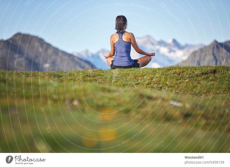 Frau meditiert in den Bergen, Rückansicht sitzend sitzt frei Friede friedlich meditieren Landschaften Berglandschaft Gebirgskette Gebirgslandschaft Gebirgszug