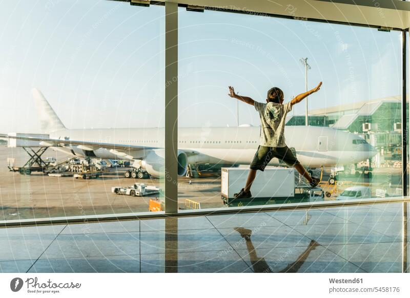 Spanien, Flughafen Barcelona, Junge im Abflugbereich, der vor eine Glasscheibe springt Europäer Kaukasier Europäisch kaukasisch Reise Travel in der Luft warten