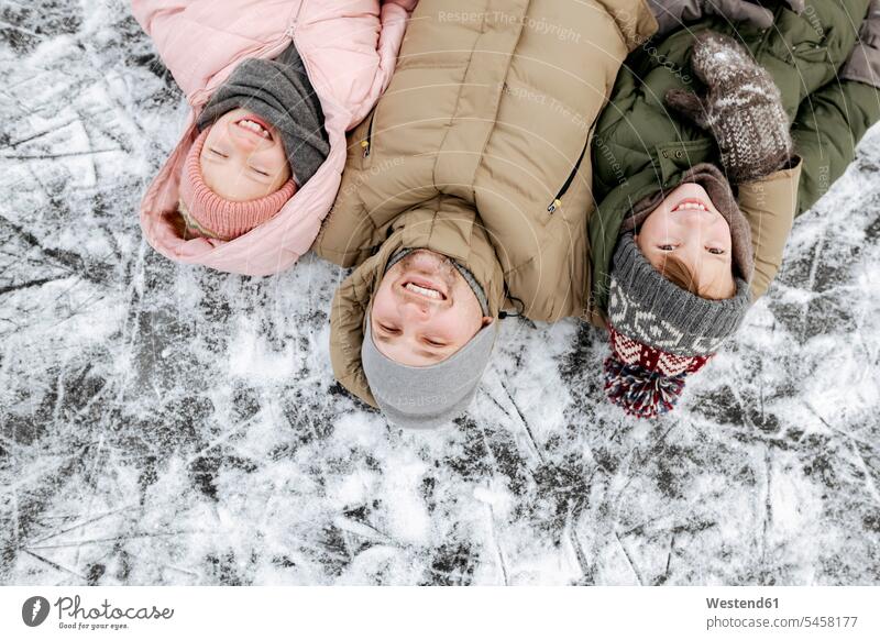 Familienporträt von Vater und zwei Kindern, die im Winter auf Eis liegen Leute Menschen People Person Personen Europäisch Kaukasier kaukasisch