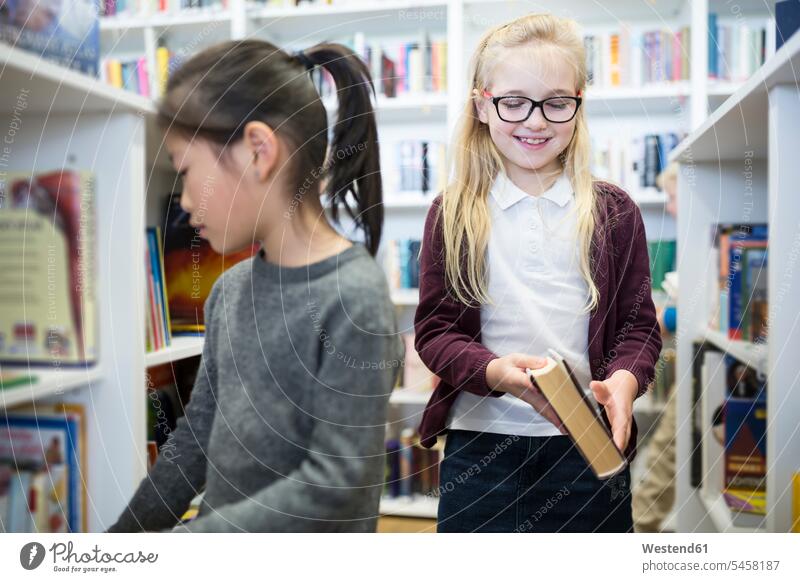 Zwei Schulmädchen in der Schulbibliothek Schule Schülerin Bücherei Buch Schulkind Bildung Wissen differenzierter Fokus Gemeinsam smart Asiatin Kind positiv
