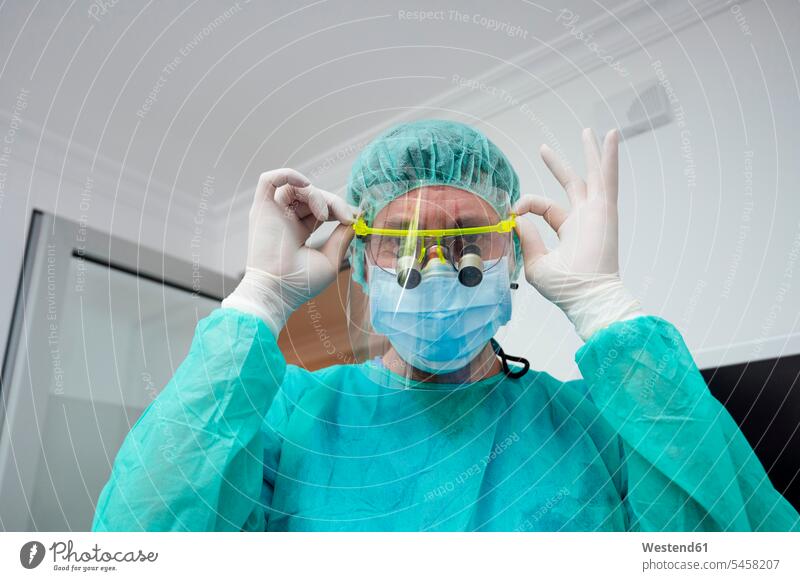 Nahaufnahme eines männlichen Zahnarztes mit Lupe im Krankenhaus Farbaufnahme Farbe Farbfoto Farbphoto Innenaufnahme Innenaufnahmen innen drinnen Medizin