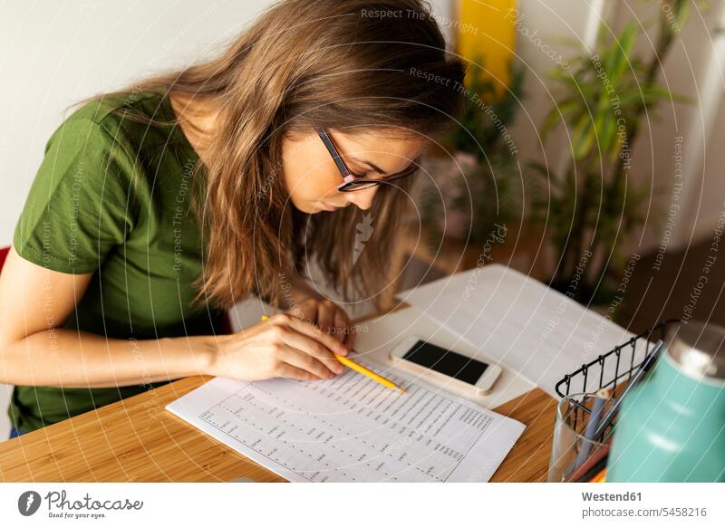 Geschäftsfrau liest Dokument auf dem Schreibtisch im Heimbüro Farbaufnahme Farbe Farbfoto Farbphoto Spanien Freizeitkleidung Freizeitbekleidung casual