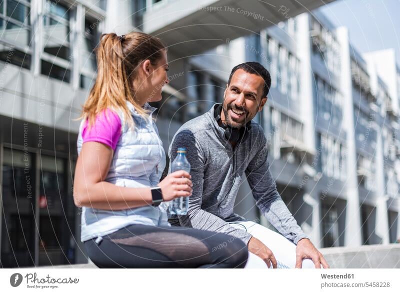 Aktives Paar mit Wasserflasche bei einer Pause in der Stadt Flasche Flaschen Wasserflaschen Pärchen Paare Partnerschaft staedtisch städtisch aktiv Mensch
