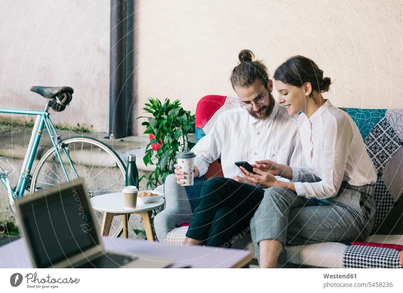 Junges Paar sitzt auf einem Sofa und benutzt ein Smartphone Leute Menschen People Person Personen Europäisch Kaukasier kaukasisch 2 2 Menschen 2 Personen zwei