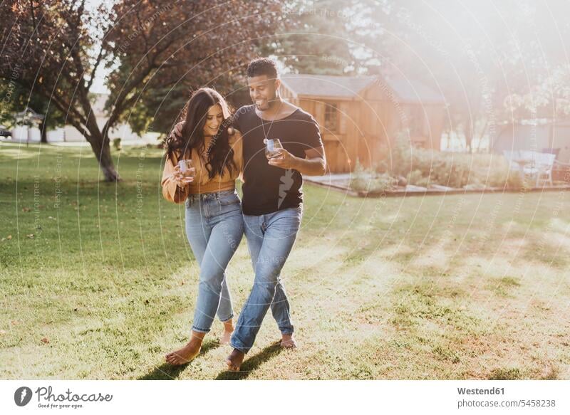 Mann und Frau halten Weinglas in der Hand, während sie im Hinterhof spazieren gehen Farbaufnahme Farbe Farbfoto Farbphoto Außenaufnahme außen draußen im Freien