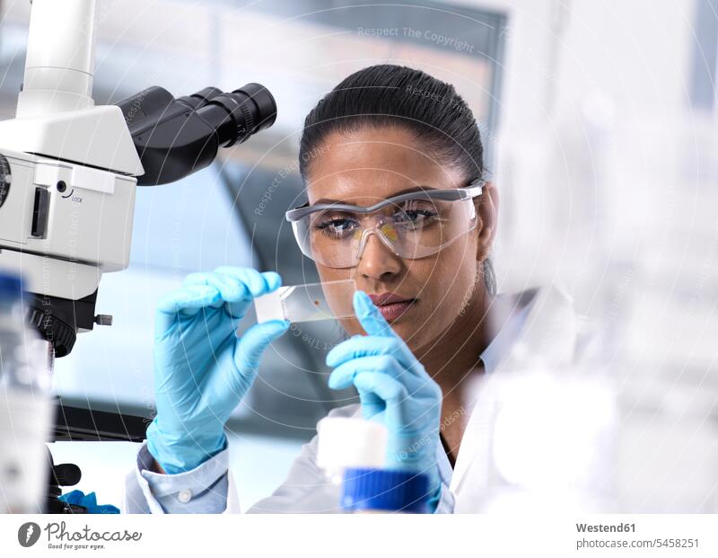 Weibliche Wissenschaftlerin untersucht eine menschliche Probe auf einem Objektträger Proben Test Tests arbeiten Arbeit Blut Menschenblut menschliches Blut Frau