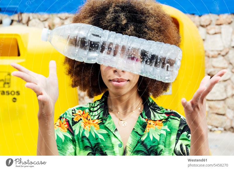 Junge Frau wirft leere Plastikflasche vor den Recycling-Behälter Rohstoffe gesammelt gelbe gelber gelbes Abfaelle Abfälle Muell Müll außen draußen im Freien