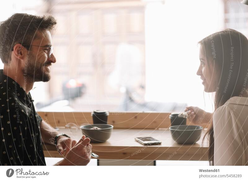 Junges Paar beim Frühstück in einem Cafe Telekommunikation telefonieren Handies Handys Mobiltelefon Mobiltelefone Brillen Flirt früh Frühe Morgen entspannen