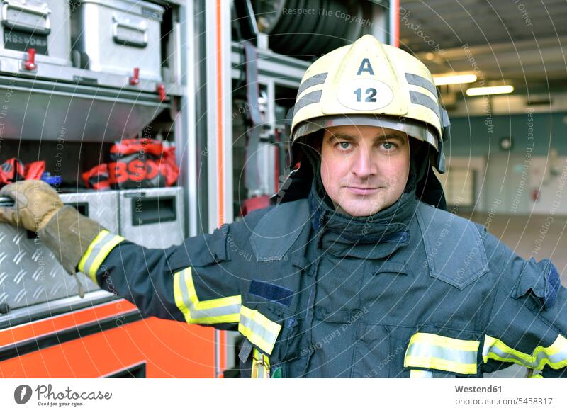Porträt eines selbstbewussten Feuerwehrmannes vor einem Feuerwehrauto Feuerwehrmaenner Feuerwehrmänner Feuerwehrleute Feuerwehrautos Feuerwehrfahrzeug