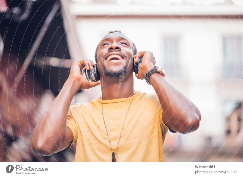 Porträt eines glücklichen Mannes, der mit Kopfhörern Musik hört und nach oben schaut T-Shirts Schmuckstueck Schmuckstuecke Schmuckstück Schmuckstücke Ketten
