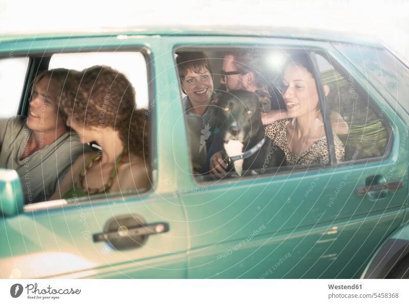 Lächelnde Freunde und Freundinnen, die während einer Autofahrt im Auto sitzen Farbaufnahme Farbe Farbfoto Farbphoto Außenaufnahme außen draußen im Freien Tag