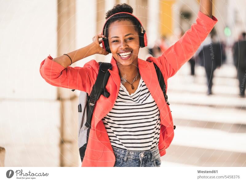 Porträt einer glücklichen jungen Frau mit Kopfhörern, die in der Stadt Musik hört, Lissabon, Portugal Kopfhoerer entspannen relaxen hoeren begeistert
