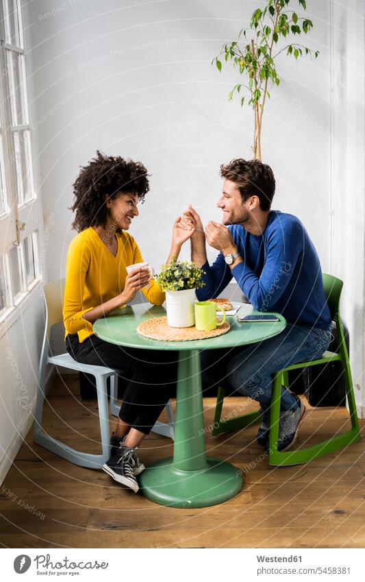 Glücklich zärtliches Paar sitzt am Tisch zu Hause Tische entspannen relaxen Flirt sitzend entspanntheit relaxt freuen geniessen Genuss glücklich sein