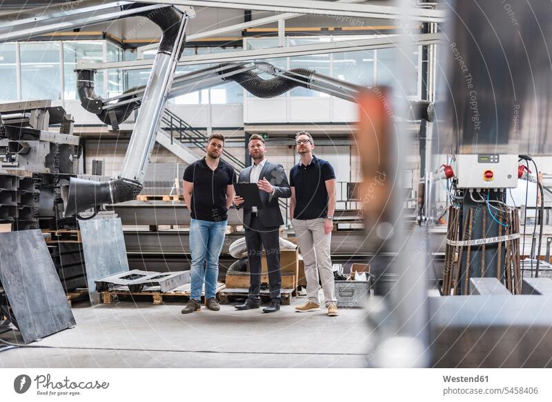 Drei Männer stehen und reden in der Fabrikhalle Produktionshalle Montagehalle sprechen stehend steht Mann männlich Fabriken Erwachsener erwachsen Mensch