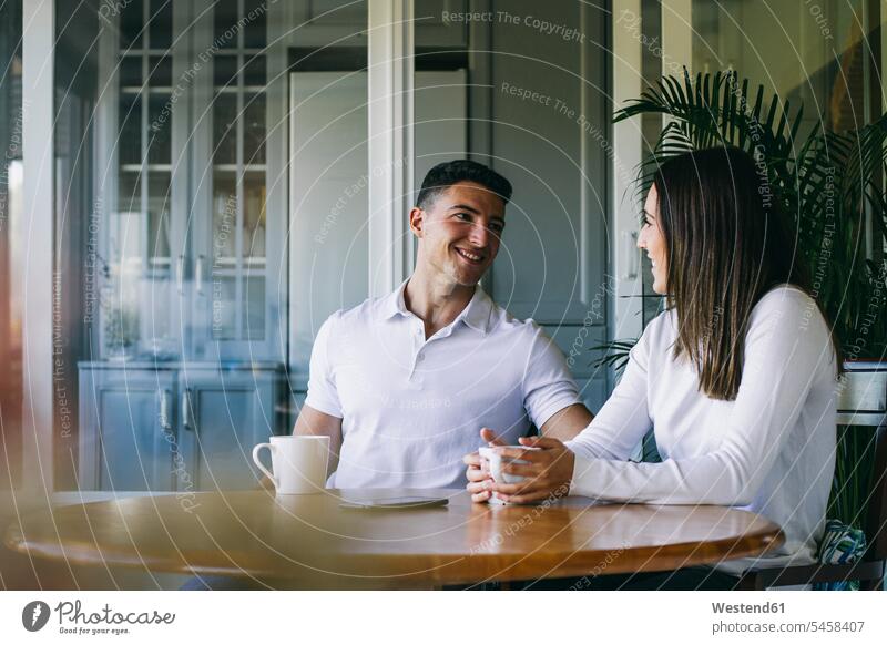 Paar trinkt Kaffee, während es zu Hause sitzt Freund Freundin Farbaufnahme Farbe Farbfoto Farbphoto Innenaufnahme Innenaufnahmen innen drinnen Tag