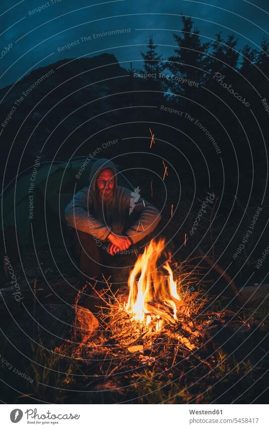 Norwegen, Lofoten, Moskenesoy, Junger Mann am Lagerfeuer sitzend Camp sitzt Feuer Europäer Kaukasier Europäisch kaukasisch brennen Zelt Zelte Camping Campen