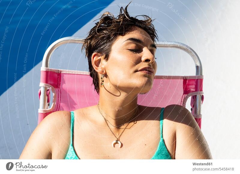 Porträt einer jungen Frau, die sich auf einer Sonnenliege am Schwimmbad entspannt weiblich Frauen Swimmingpool Swimmingpools Schwimmbecken Swimming Pool