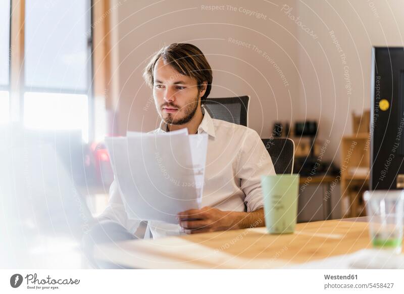 Geschäftsmann liest Dokument am Schreibtisch im Büro Job Berufe Berufstätigkeit Beschäftigung Jobs geschäftlich Geschäftsleben Geschäftswelt Geschäftsperson