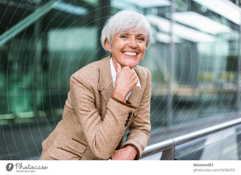 Porträt einer lächelnden älteren Geschäftsfrau, die sich auf ein Geländer in der Stadt stützt Geschäftsfrauen Businesswomen Businessfrauen Businesswoman
