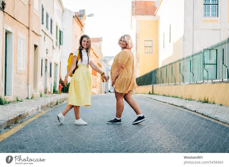 Lächelnde Freunde gehen gemeinsam auf der Straße in der Stadt Farbaufnahme Farbe Farbfoto Farbphoto Außenaufnahme außen draußen im Freien Tag Tageslichtaufnahme