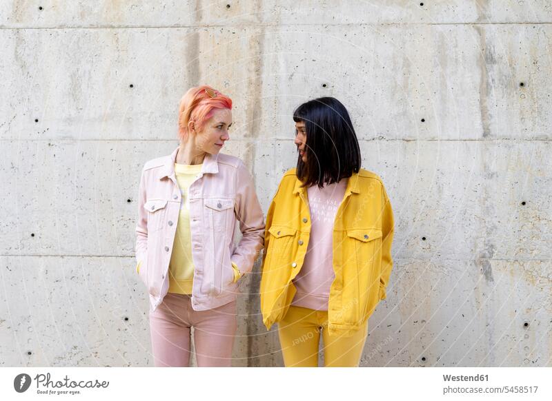 Zwei alternative Freunde, die Spaß haben, in gelber und rosa Jeansbekleidung, von Angesicht zu Angesicht Freundinnen Alternative Lesbe Lesben Lesbierin