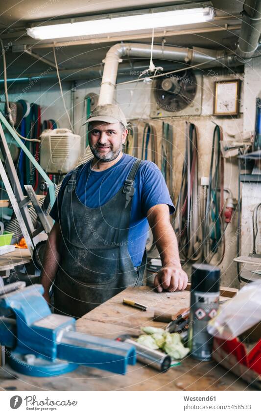 Porträt eines selbstbewussten Messermachers in seiner Werkstatt Job Berufe Berufstätigkeit Beschäftigung Jobs Berufsbekleidung Overall Geräte Werkzeuge