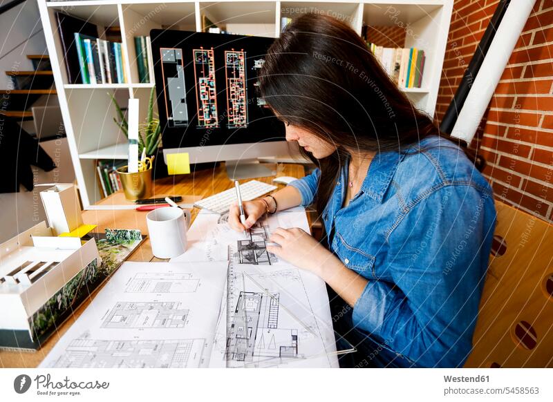 Junge Frau, die im Architekturbüro arbeitet und Blaupausen zeichnet Bauplan Architekturplan Konstruktionsplan Konstruktionszeichnung Bauzeichnung entwerfen