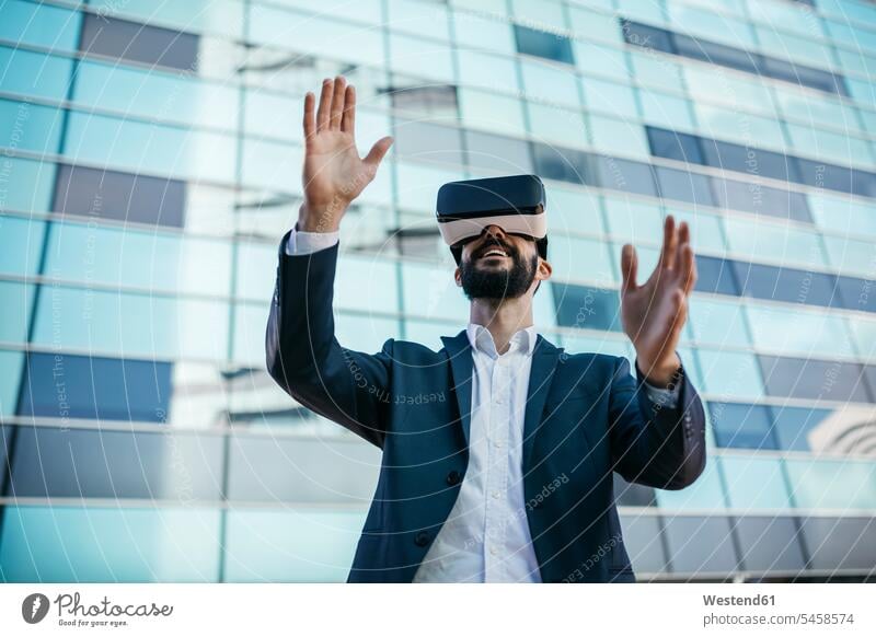 Geschäftsmann mit Virtual-Reality-Brille vor dem Bürogebäude Brillen Bürohaus Bürohäuser Virtuelle Realität Virtuelle Realitaet VR Businessmann Businessmänner
