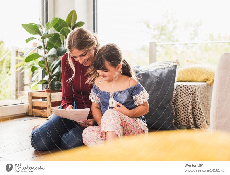 Mutter hilft Tochter bei den Hausaufgaben zu Hause Papiere Stifte aufschreiben notieren schreibend Schrift sitzend sitzt entspannen relaxen entspanntheit relaxt