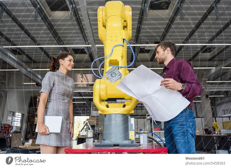 Geschäftsmann und Frau bei einem Treffen vor Industrierobotern in einem High-Tech-Unternehmen Team Wartung Herstellung Roboter Tablet Tablet Computer Tablet-PC