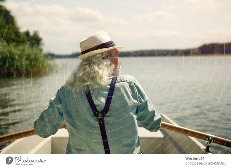 Rückenansicht eines älteren Mannes, der in einem Ruderboot auf einem See sitzt und Hosenträger und Sommerhut trägt Hosentraeger Boot Boote Ruderboote Sommerhüte