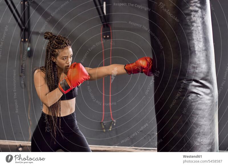 Boxerin mit roten Handschuhen übt Boxübung am Boxsack in Turnhalle Farbaufnahme Farbe Farbfoto Farbphoto Südafrika Afrika Innenaufnahme Innenaufnahmen innen