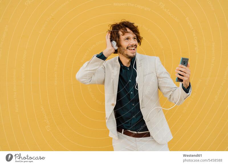 Porträt eines singenden Geschäftsmannes, der mit Kopfhörer und Smartphone singt und Musik hört geschäftlich Geschäftsleben Geschäftswelt Geschäftsperson
