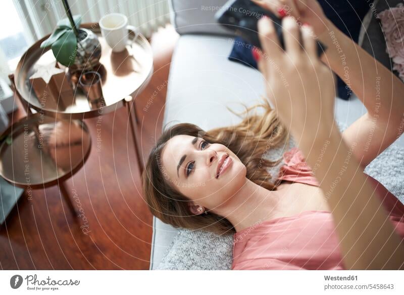 Junge Frau im Morgenmantel liegt im Bett und benutzt ein Mobiltelefon liegen liegend lächeln weiblich Frauen Handy Handies Handys Mobiltelefone Betten