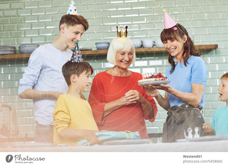 Mutter und Söhne feiern den Geburtstag der Großmutter in ihrer Küche daheim zu Hause drinnen Innenaufnahmen Geschenke schenken Fest Festtag Festtage Geburtstage