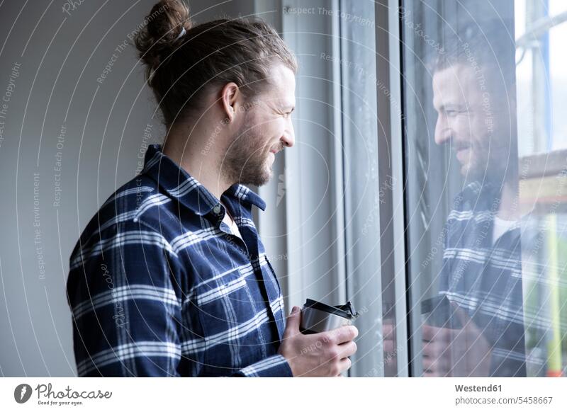 Bauarbeiter mit Container in der Hand, der zu Hause durch ein Fenster schaut Farbaufnahme Farbe Farbfoto Farbphoto Deutschland Architektur Baukunst Baustelle