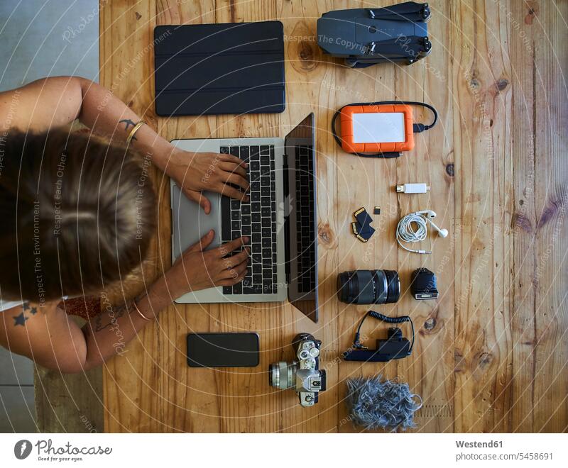 Am Tisch sitzende Person mit fotografischer Ausrüstung, mit Laptop, Draufsicht Job Berufe Berufstätigkeit Beschäftigung Jobs Fotografen Photograph Photographen