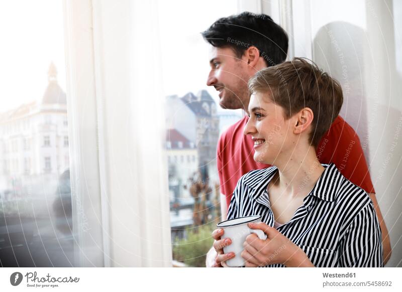 Entspanntes Paar steht am Fenster, Frau trinkt Kaffee entspannt entspanntheit relaxt trinken stehen stehend glücklich Glück glücklich sein glücklichsein Pärchen