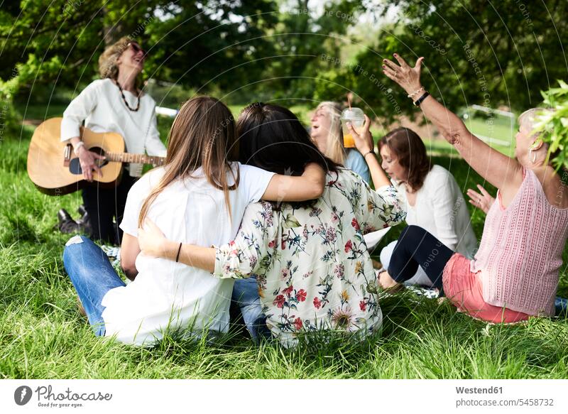 Gruppe von Frauen mit Gitarre haben Spaß bei einem Picknick im Park Spass Späße spassig Spässe spaßig weiblich picknicken Parkanlagen Parks Freundinnen