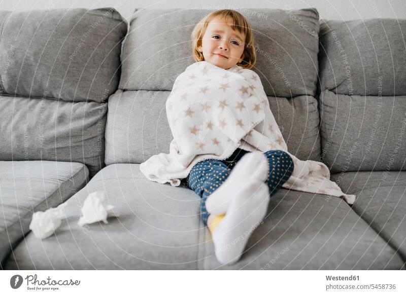 Porträt eines kranken kleinen Mädchens, das in eine Decke gehüllt zu Hause auf der Couch sitzt Decken Struempfe Strümpfe Socke Couches Liege Sofas