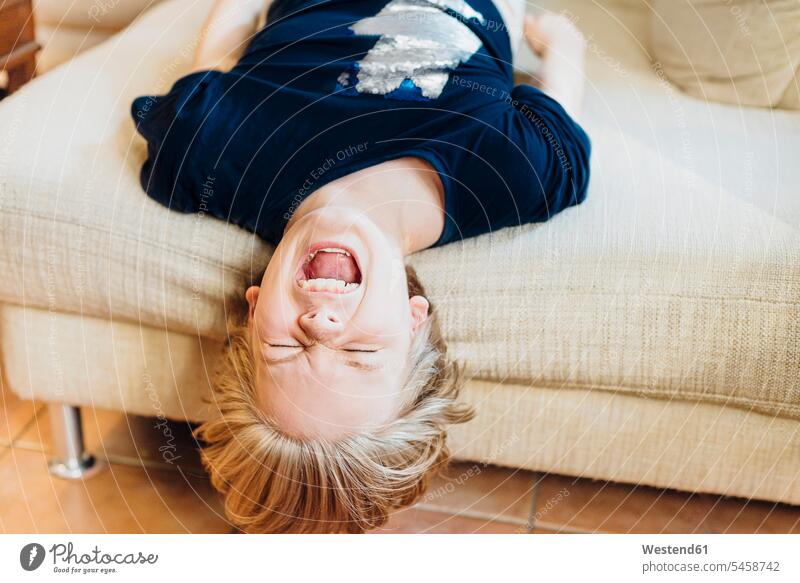 Schreiender Junge auf der Couch liegend T-Shirts Couches Liege Sofas liegt daheim zu Hause Muße Geräusch Krach laut gefühlvoll Emotionen Empfindung Empfindungen