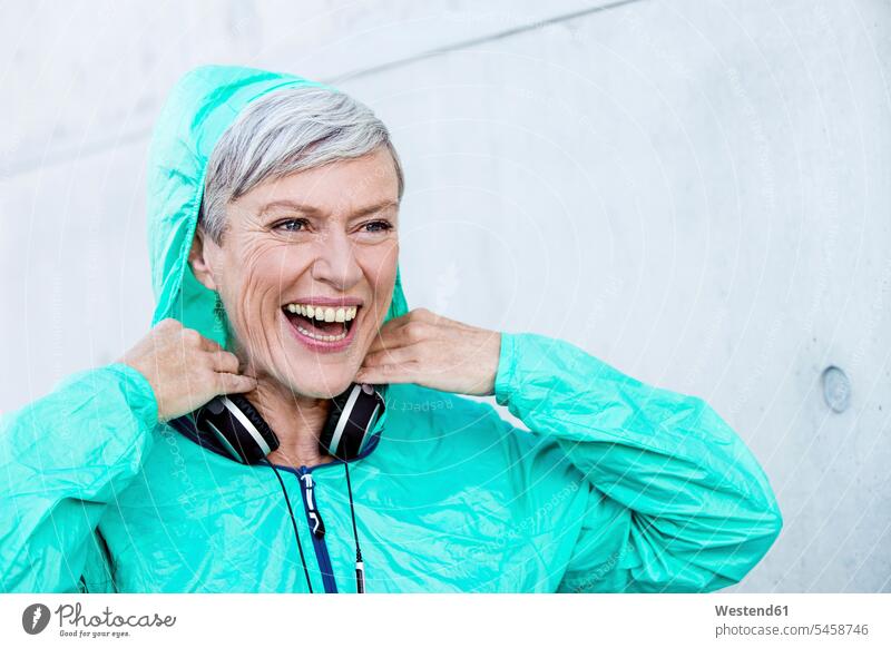 Porträt einer lachenden sportlichen reifen Frau mit Kopfhörern Portrait Porträts Portraits Kopfhoerer weiblich Frauen Sport positiv Emotion Gefühl Empfindung