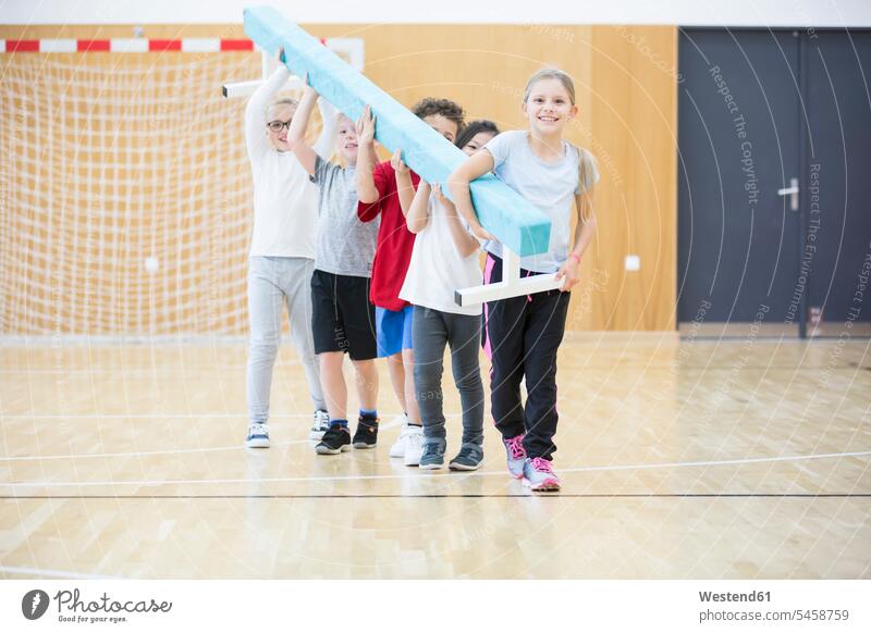 Schülerinnen und Schüler mit Balancierbalken im Sportunterricht Schwebebalken tragen transportieren Schule Schulen Schulkind Schueler Schulkinder Bildung