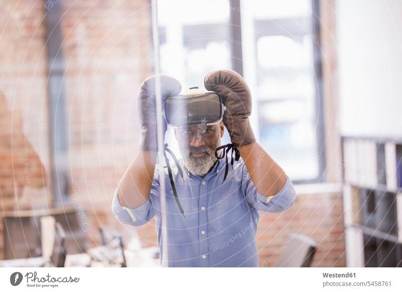Portrait eines Geschäftsmannes mit Virtual-Reality-Brille und Boxhandschuhen im Büro Virtual Reality Brille Virtual Reality-Brille VR Brille Office Büros Boxen