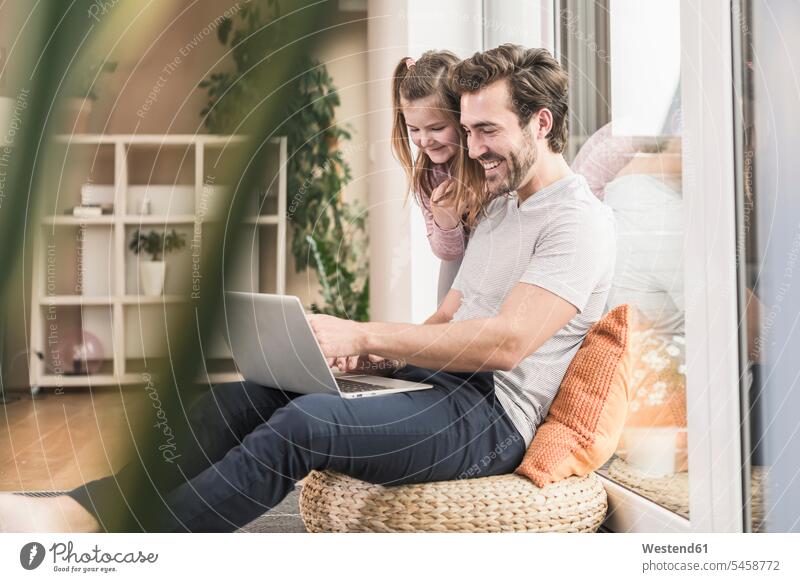 Junger Mann und kleines Mädchen surfen zusammen im Netz Deutschland differenzierter Fokus auf dem Boden sitzen auf dem Boden sitzend Laptop benutzen
